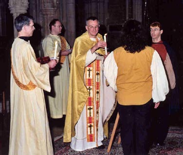 A scene from the re-enactment of a same-sex union ceremony in a church in Croydon. The priest is about to give lighted candles to the couple being joined together.